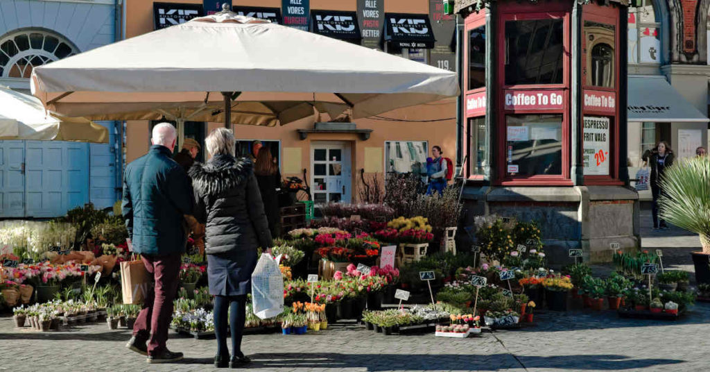 Koppel op leeftijd staat voor een bloemenwinkel op een zonnige dag